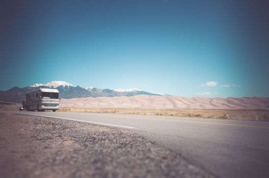 Recreation Vehicle with a Tow on the Colorado Road near Great Sand Dunes. Traveling in Class A RV Motorhome in America.