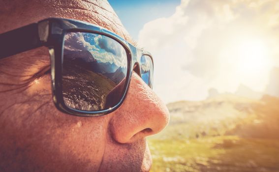 Sunglasses Protection. Caucasian Men in His 50s in the Trendy Black Sunglasses. Closeup Photo. Mountains Reflection in the Lenses.