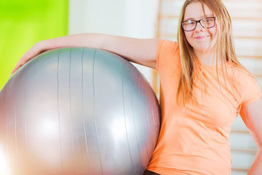 Exercise Ball Time. Young Caucasian Girl with Large Exercise Ball in Hand. Rehabilitation Concept Photo.