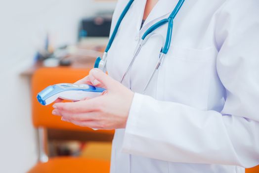 No Touch Thermometer in Physicians Hands. Using Touch Free Forehead Thermometer. Doctor Office. Checking Forehead Temperature