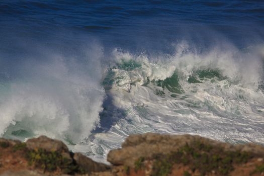 Marine wave breaks against offshore stone