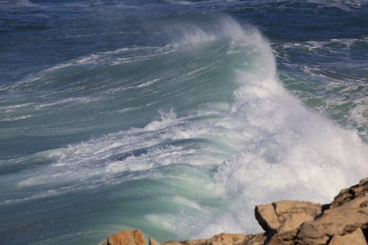 Marine wave breaks against offshore stone