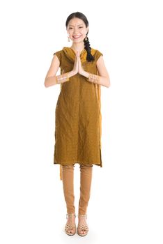 Portrait of young mixed race Indian Chinese girl in traditional punjabi dress greeting, full length standing isolated on white background.