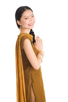 Portrait of young mixed race Indian Chinese female in traditional punjabi dress greeting, standing isolated on white background.