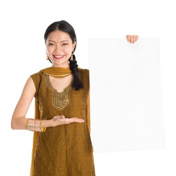 Portrait of young mixed race Indian Chinese girl in traditional punjabi dress holding a blank white placard, standing isolated on white background.