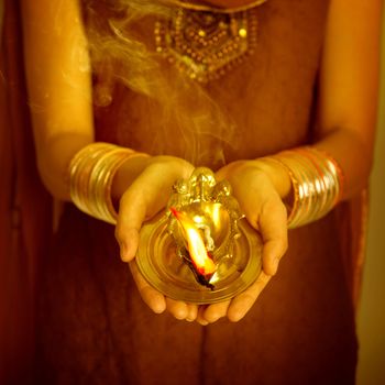 Close up Indian woman in traditional sari hands holding diya and celebrating Diwali or deepavali, fesitval of lights.