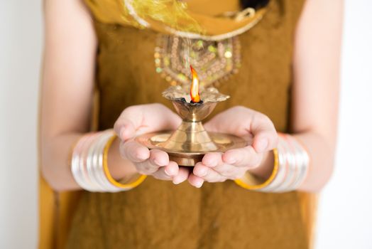 Close up fair Indian woman in traditional dress hands holding diya oil lamp and celebrating Diwali or deepavali, fesitval of lights.