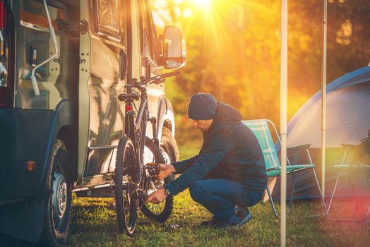 Fall Camping Time. Motorhome and Tent Camping. Men Preparing His Mountain Bike For a Trip.