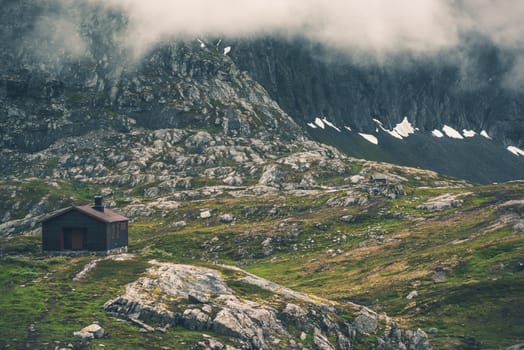 Raw Norwegian Mountain Landscape with Rustic Cabins. Cloudy Norway Mountains.