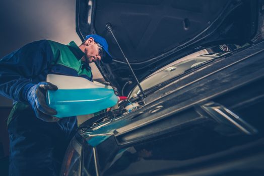 Refilling Car Windshield Washer Fluid by Professional Car Service Technician.