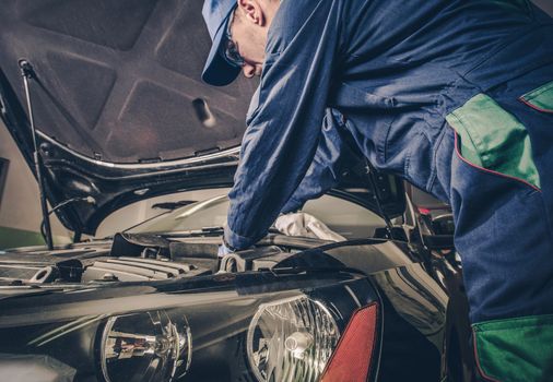 Auto Service Business Concept. Pro Car Mechanic Taking Care of Vehicle. Checking Under the Car Hood.