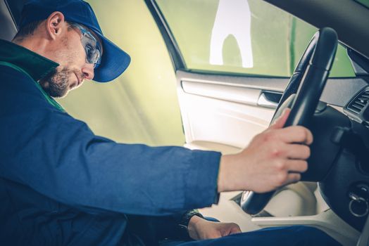 Professional Car Mechanic Examining Electronic Systems of the Car While Seating Inside. Car Maintenance and Inspection.