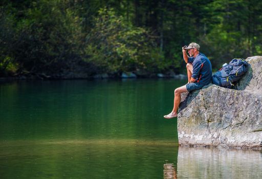 Adventurous Men Resting on the Scenic Lake Boulder. Scenic Lake Trail Hiker.