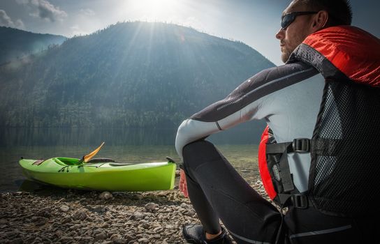 Caucasian Kayaker in the Sun. Kayaker Enjoying Scenic View While Seating on the Lake Shore.