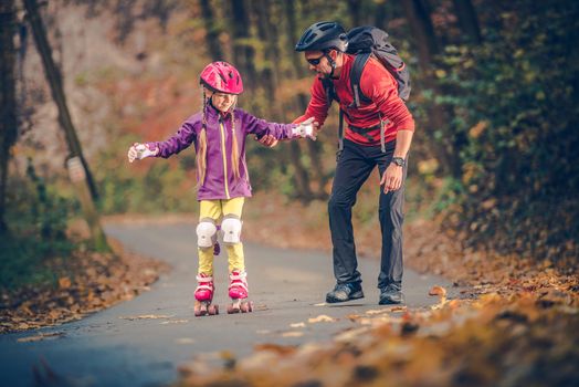 Roller Skate Family Learning. Father Teach His Daughter How to Roller Skating. Outdoor Caucasian Family Recreation