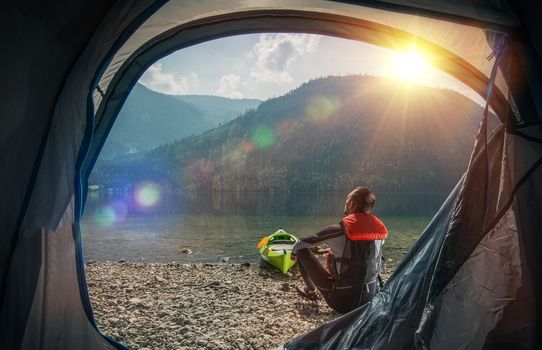 Tenting and Kayaking on the Lake. Caucasian Sportsman Camping and Kayaking on the Scenic Mountain Lake Shore.