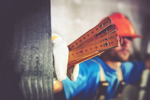 Construction Worker with Measuring Tool Closeup Photo. Home Construction Site Theme.