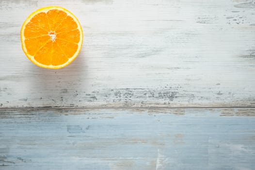 One slice of fresh oranges on painted wooden board, looks like sun at sky over a sea, copy space