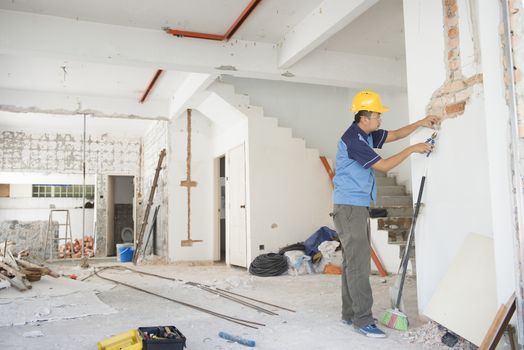 House renovation concept. Asian construction worker with hardhat working.