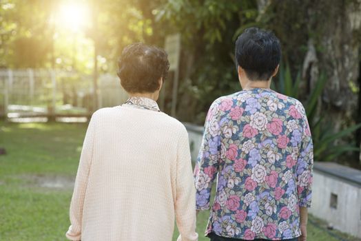 Candid shot of rear view Asian old women walking at outdoor park in the morning.