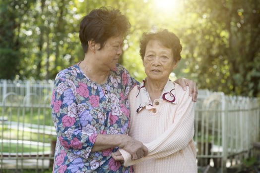 Candid shot of Asian elderly women holding hands at outdoor park in the morning.