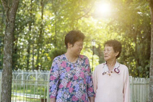 Candid shot of Asian senior adult women walking at outdoor garden park in the morning.