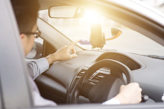 Business Man in the car and using mobile phone with map gps navigation, toned at sunset.