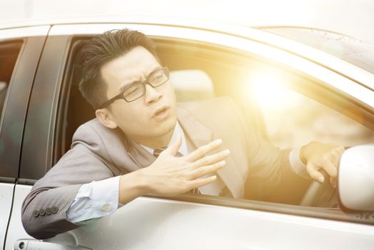 Close up portrait of angry young business man pissed off by drivers in front of him. Road rage traffic jam concept.