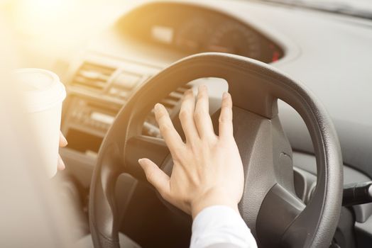 Concept photo of close up hand on steering honking while driving in morning.