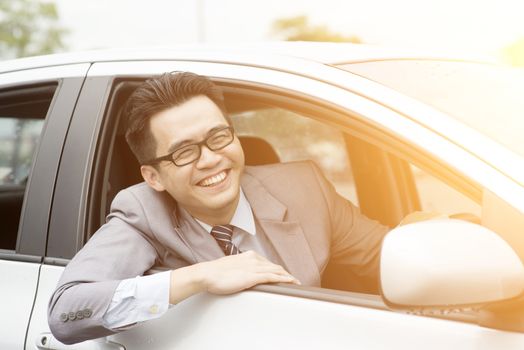 Happy Asian driver sitting in his car and smiling.