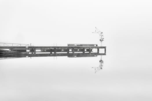 Lonely dock in a foggy and calm day
