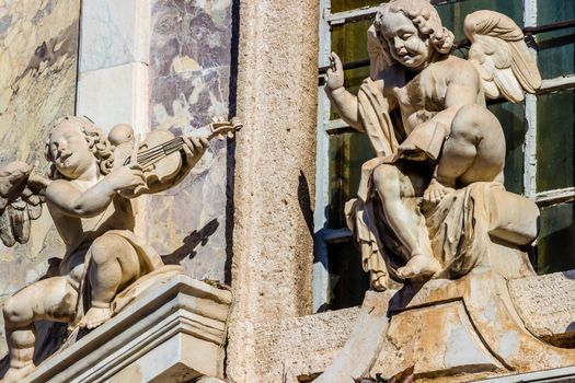 the statues of two cherub with musicla instrument