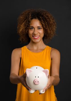 Portrait of a beautiful African American woman holding a Piggybank