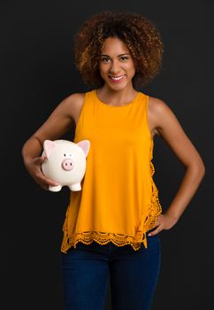 Portrait of a beautiful African American woman holding a Piggybank