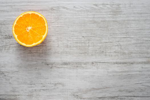 Single round slice of fresh orange on white wood background, Top view, lot of copyspace