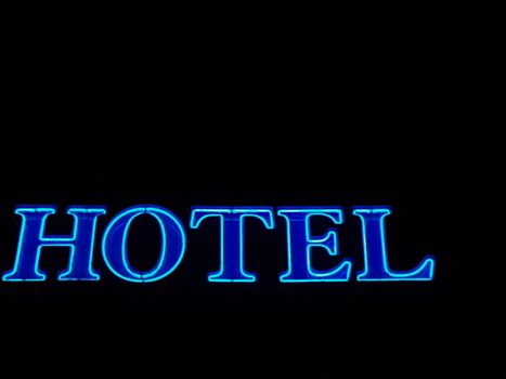 Bright blue hotel neon sign against black background