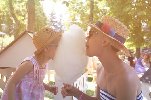 Child eats cotton candy with mom in city street. Effect retro film