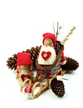 Christmas Decoration Concept with Handmade Dolls in Knit Hats, Fir Cones, Sleigh and Marshmallows on Wooden Sticks closeup on White background. Retro Styled
