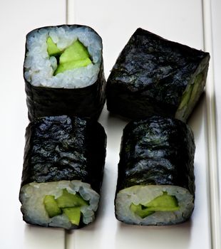 Vegetarian Cucumber Sushi with Rolled in Nigiri closeup on White Plank background