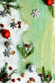 Christmas Greeting Background with Border of Green Branches, Snow Flakes, Red Baubles and Silver Stars closeup on Cracked Wooden background