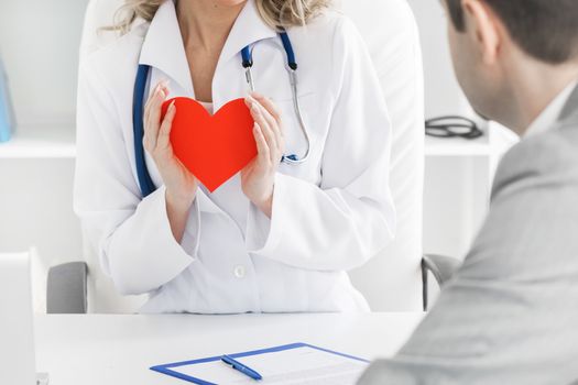 Doctor showing red paper heart to patient, cardio therapeutist consultation