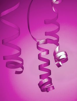 Three Purple Curled Party Streamers isolated on Blurred Pink-Purple background