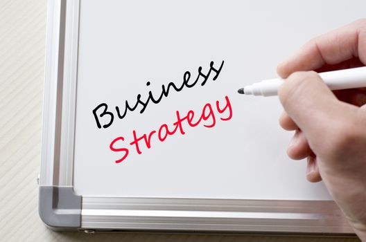 Human hand writing business strategy on whiteboard