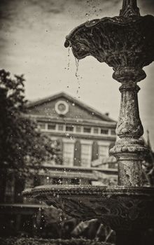 Sepia toned fountain dripping with cool water, Jackson Square Park, New Orleans, Louisiana with historical building in the background