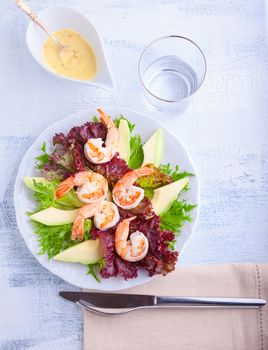 Avocado shrimp salad with mustard sauce on a white plate