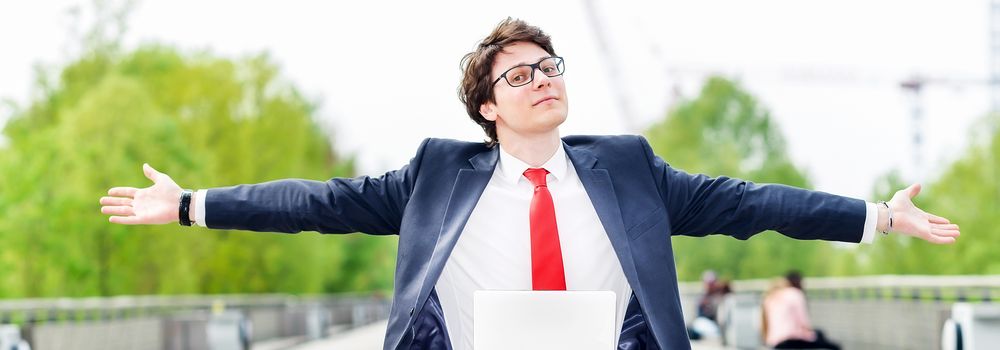 panoramic view of dynamic young executive working outside free of any constraint. Arms outstretched, symbolizing a job search or a trade of outsourcing