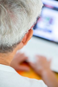 An old person with a pair of glasses in front of a laptop screen