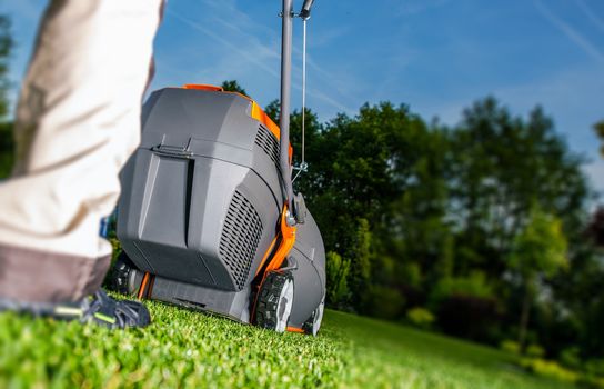 Summer Lawn Mowing and Backyard Landscaping. Men with Grass Mower.