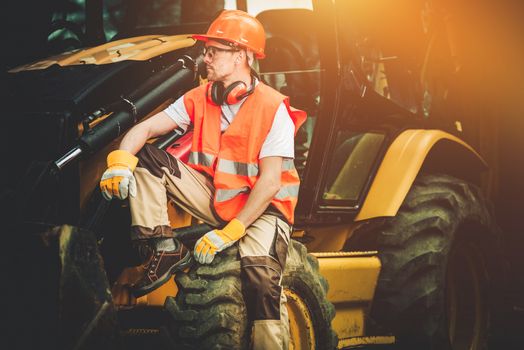 Bulldozer Construction Worker Resting on His Heavy Duty Machinery.