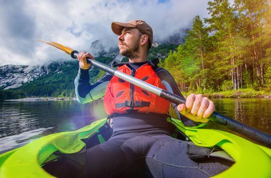 Kayak River Trip in Norway. Men in the Green Kayak Paddling and Enjoying the Moment. Scenic Landscape.